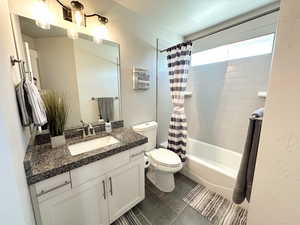 Full bathroom featuring shower / tub combo with curtain, vanity, and dark tile patterned flooring