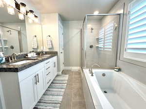 Bathroom with a garden tub, a stall shower, double vanity, and light tile patterned floors