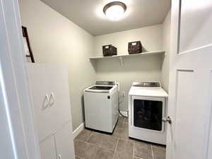 Laundry area featuring independent washer and dryer and dark tile patterned floors