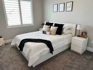 Bedroom with dark carpet and baseboards