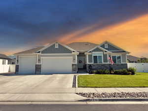 Craftsman-style house with board and batten siding, stone siding, an attached garage, concrete driveway, and roof with shingles
