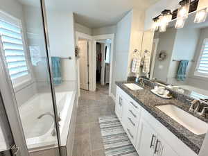Full bathroom with double vanity, a garden tub, light tile patterned floors, and a stall shower