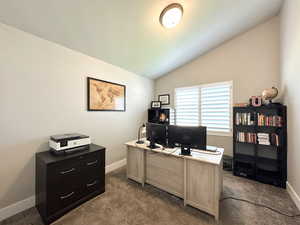 Home office with vaulted ceiling and dark carpet