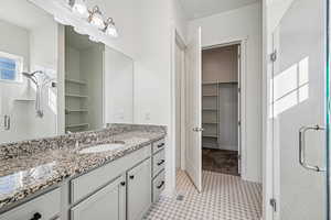 Full bath featuring a walk in closet, a stall shower, and vanity