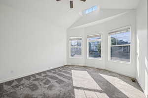 Unfurnished room featuring carpet, high vaulted ceiling, and a ceiling fan