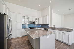 Kitchen featuring appliances with stainless steel finishes, white cabinetry, light stone counters, a center island, and recessed lighting
