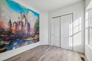 Unfurnished bedroom with wood finished floors and a closet