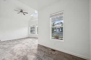 Spare room with a skylight, lofted ceiling, carpet flooring, and a ceiling fan