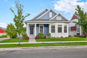 View of front of property featuring covered porch and a front yard