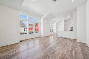 Unfurnished living room with recessed lighting, light wood-style flooring, and a chandelier