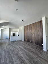 Unfurnished living room with wooden walls, dark wood-style flooring, a chandelier, and recessed lighting