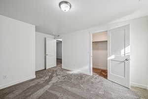 Unfurnished bedroom with a spacious closet and carpet floors