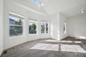 Carpeted empty room featuring plenty of natural light and a high ceiling
