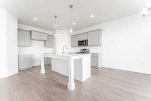 Kitchen with gray cabinets, a breakfast bar, pendant lighting, stainless steel appliances, and recessed lighting
