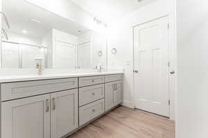 Bathroom with a shower stall, double vanity, and light wood-style floors