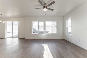 Empty room featuring light wood-style flooring, a chandelier, and ceiling fan
