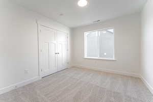 Unfurnished bedroom featuring light carpet and a closet