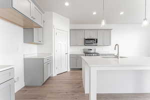 Kitchen with gray cabinets, hanging light fixtures, and recessed lighting