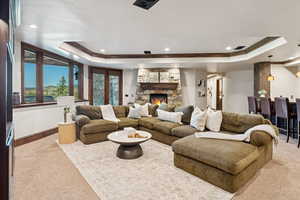 Living area with carpet, a tray ceiling, crown molding, recessed lighting, and a fireplace