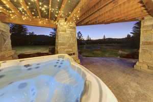 Patio terrace at dusk with a hot tub, a yard, and a patio area