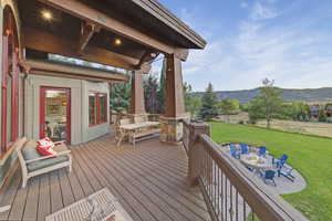 Deck featuring outdoor dining area, a lawn, a mountain view, and a fire pit