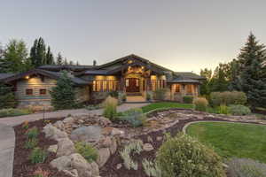 View of front of property featuring covered porch, stone siding, and a front lawn