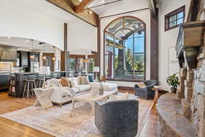 Living area with beam ceiling, light wood finished floors, and high vaulted ceiling