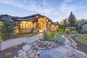 View of front of home featuring stone siding, covered porch, and a small pond