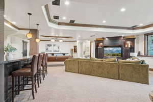 Living room with a tray ceiling, crown molding, arched walkways, recessed lighting, and light carpet