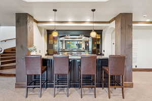 Indoor wet bar with light carpet, stairway, light stone counters, pendant lighting, and recessed lighting