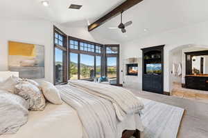 Carpeted bedroom with beamed ceiling, a tiled fireplace, recessed lighting, a ceiling fan, and access to outside