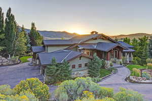 View of front of property featuring stone siding, roof with shingles, a mountain view, and a chimney