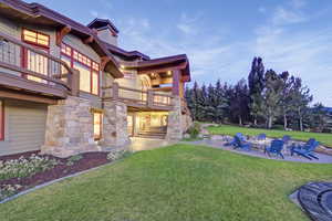 View of grassy yard featuring a patio area, an outdoor fire pit, and a balcony