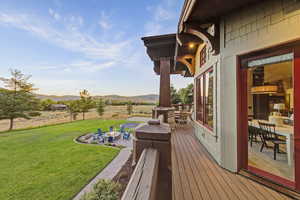 Wooden terrace with a yard, a fire pit, a view of rural / pastoral area, outdoor dining space, and a patio area