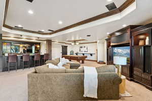Living area with a raised ceiling, billiards table, ornamental molding, light carpet, and recessed lighting