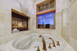 Full bath featuring a whirlpool tub and tile walls