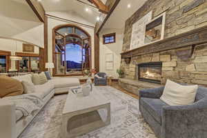Living room featuring beamed ceiling, a stone fireplace, wood finished floors, high vaulted ceiling, and a mountain view