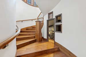Stairs featuring wood finished floors and a high ceiling