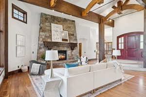 Living area featuring a fireplace, plenty of natural light, a high ceiling, beamed ceiling, and wood finished floors