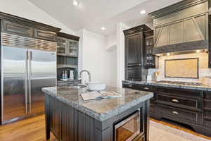 Kitchen with built in appliances, glass insert cabinets, backsplash, light stone counters, and recessed lighting