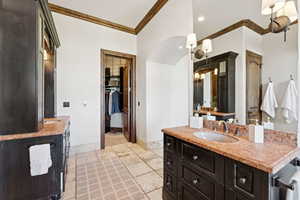 Full bath with vanity, ornamental molding, a spacious closet, recessed lighting, and stone tile floors