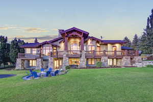 Back of property featuring a yard, stone siding, an outdoor fire pit, and a balcony
