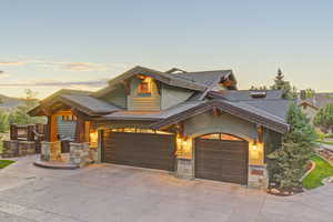 Craftsman house featuring a standing seam roof, stone siding, a metal roof, concrete driveway, and an attached garage