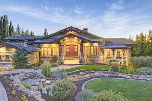 View of front of house featuring a standing seam roof, stone siding, a metal roof, a chimney, and a front yard