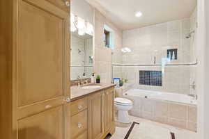 Full bath with tile walls, tiled shower / bath combo, light tile patterned flooring, vanity, and recessed lighting