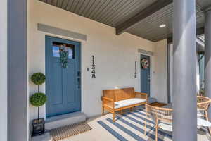 Doorway to property with stucco siding and covered porch