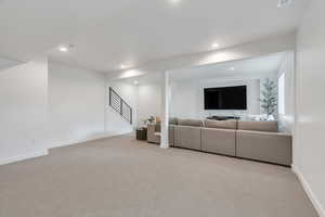 Living area with carpet flooring, recessed lighting, and stairway