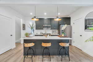 Kitchen with tasteful backsplash, appliances with stainless steel finishes, recessed lighting, a kitchen breakfast bar, and light wood finished floors
