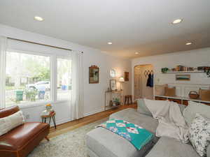 Living room with arched walkways, wood finished floors, crown molding, and recessed lighting