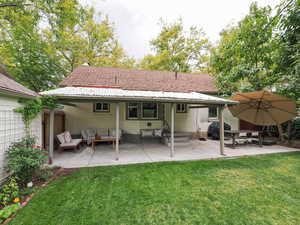 Back of property featuring brick siding, outdoor lounge area, a lawn, and a patio area